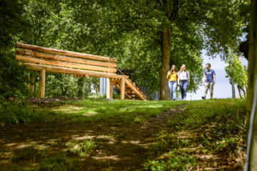 Drie wandelaars langs de grote houten wijnbank op de Houwaartse Berg.