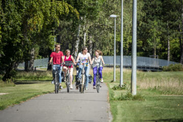 Groepje mensen fietst samen op verharde weg in het provinciedomein Kessel-Lo.
