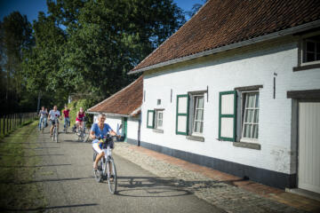 Groepje fietst langs witte hoeve.