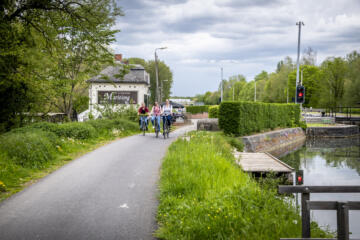 Drie fietsers fietsen langs het kanaal aan Sas Tildonk en café Maritime.