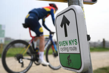 Wielrenner Tibo Nys fietst langs een bewegwijzeringsbordje van de Sven Nys Cycling route